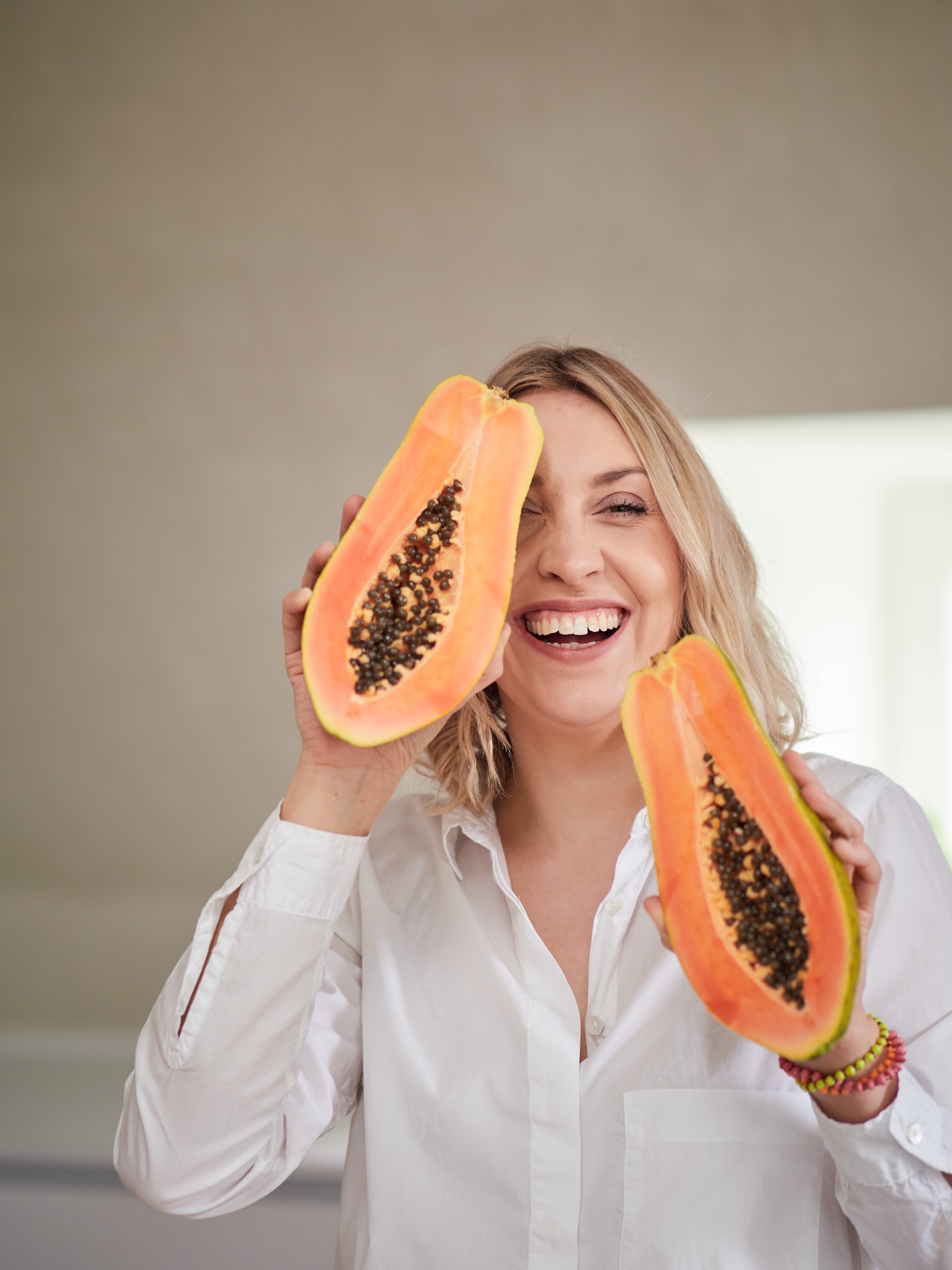 Kemja-Maria lacht mit zwei Papaya-Hälften in den Händen