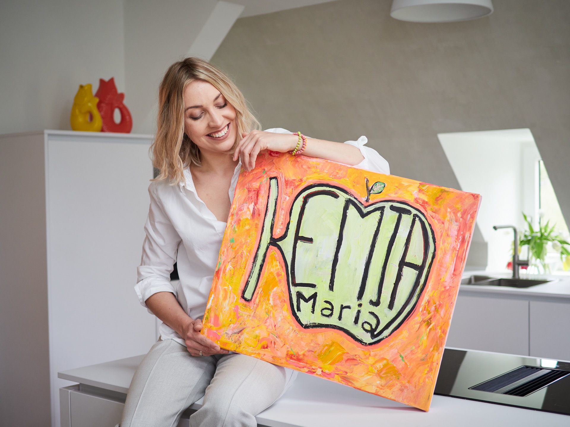 Kemja-Maria zeigt das gemalte Kemja-Markenbild